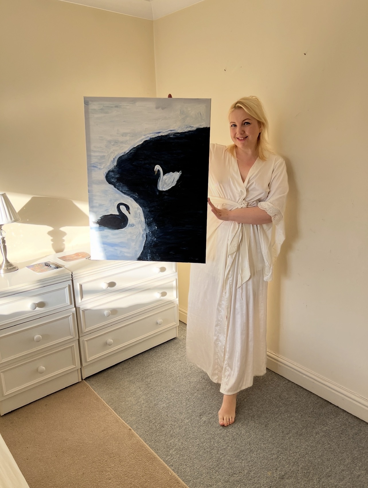 Marina Stognieva holding the completed painting Swans. Harmony in the United Kingdom, 2025